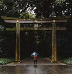 鳥居前で一人が傘をさして立っている